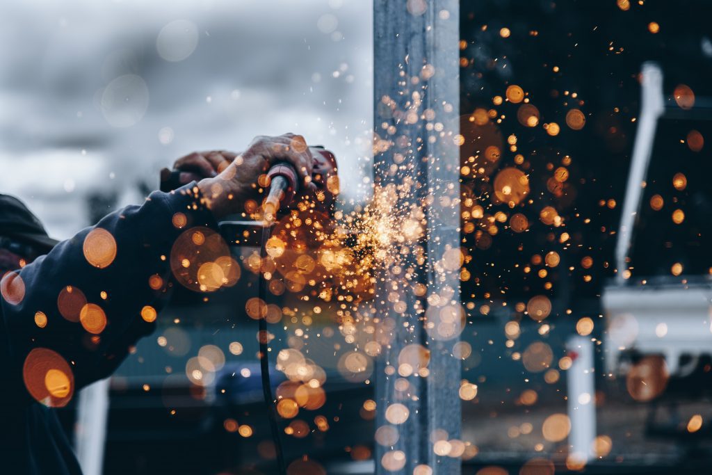 A person welding and throwing up bright orange sparks