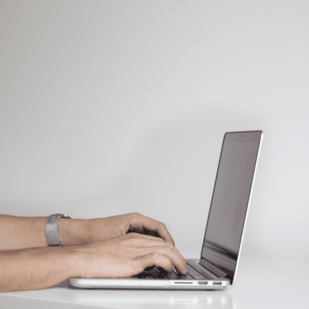 Two hands typing on a laptop